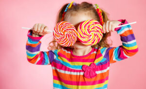 Playful little girl holds large lollipops in front of her eyes